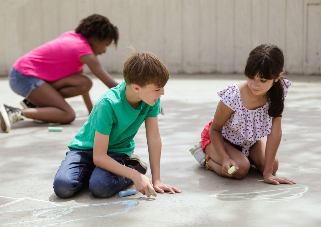 enfants qui écrivent et dessinent au sol