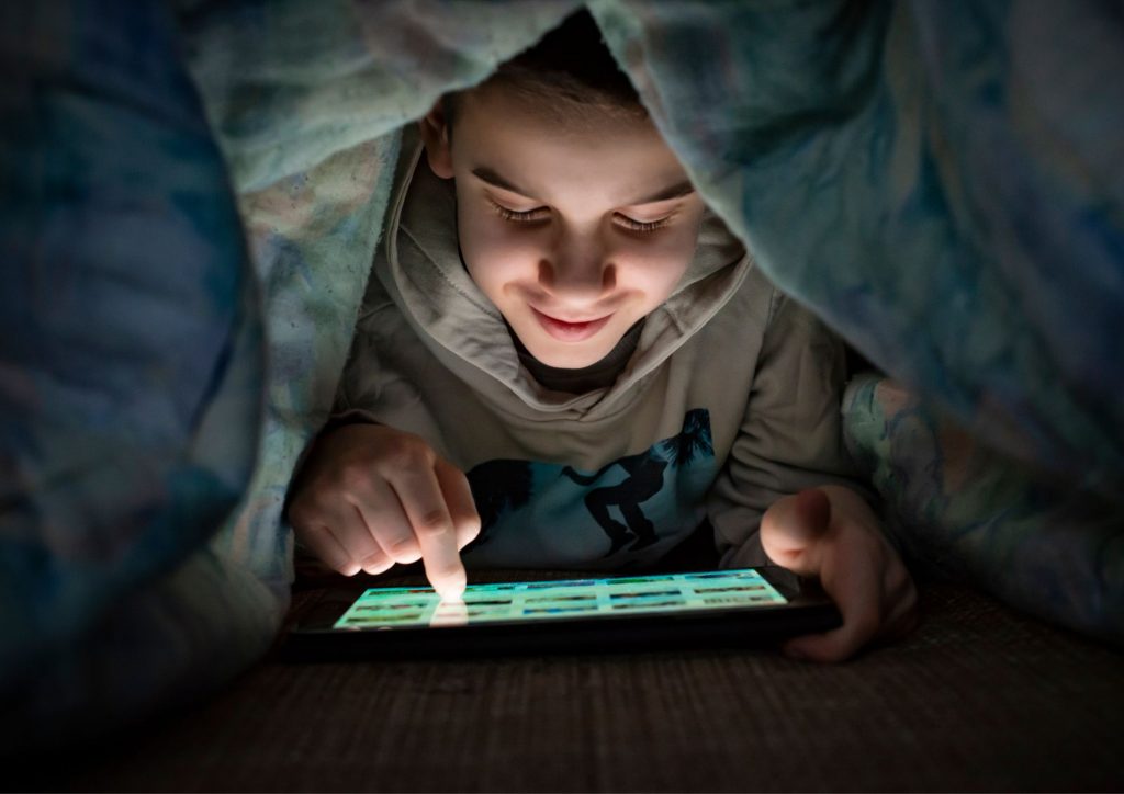 enfant consultant une tablette dans sa chambre