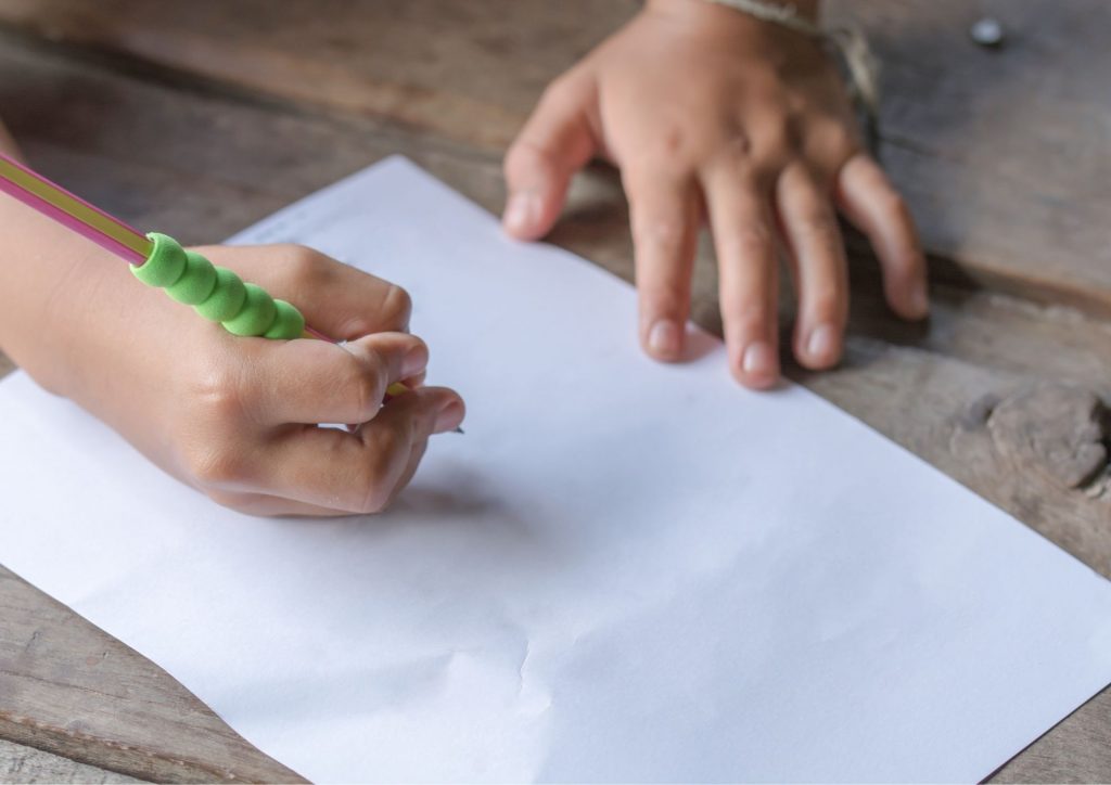 enfant qui écrit au crayon sur une feuille