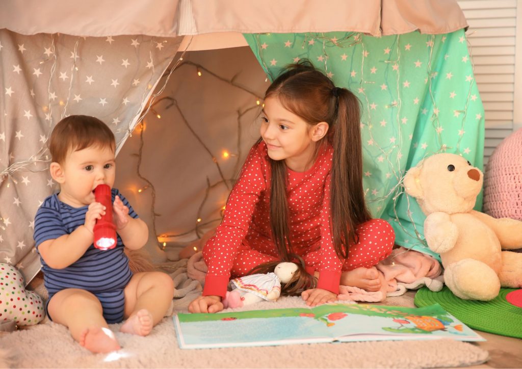 grande fille avec son petit frère dans une cabane en tissu