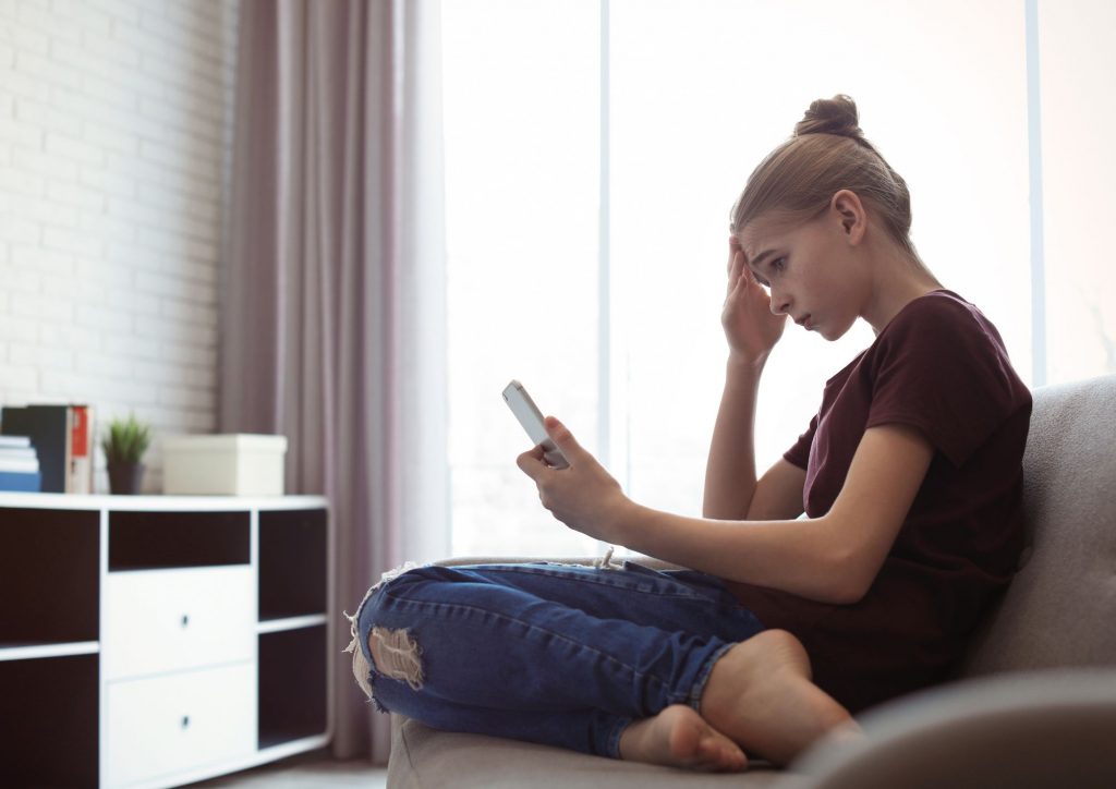 jeune fille inquiète qui consulte Internet sur son smartphone